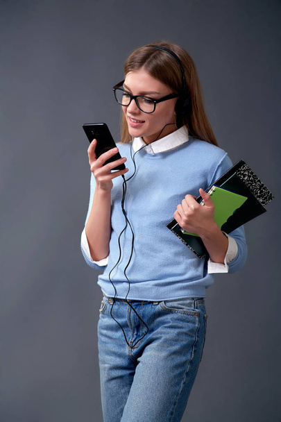 Student holding smartphone and notebooks. Student concept. Studio - Photo, Image