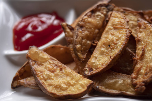 A plate with fried golden potatoes in country style with tomato sauce - 写真・画像