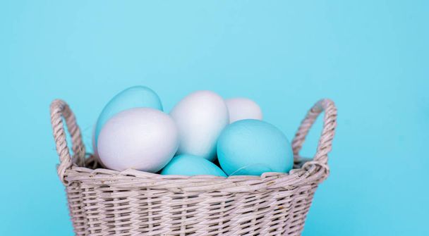 Traditional painted Easter eggs in white basket, pastel color background. Spring and Easter holiday concept. - Photo, image