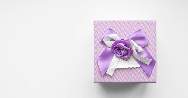 Top view of purple gift box with satin ribbon bow on white background - Foto, Imagem