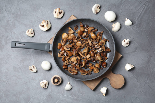 Frying pan with mushrooms on grey background, flat lay - Foto, immagini