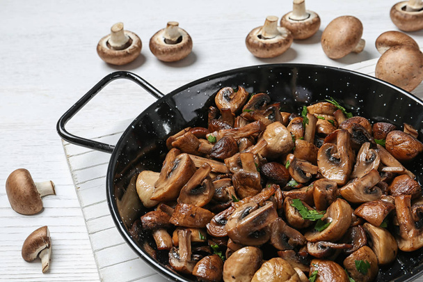 Frying pan with mushrooms on table, closeup - Fotó, kép