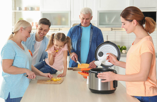 Onnellinen perhe valmistaa ruokaa moderni multi liesi keittiössä
 - Valokuva, kuva