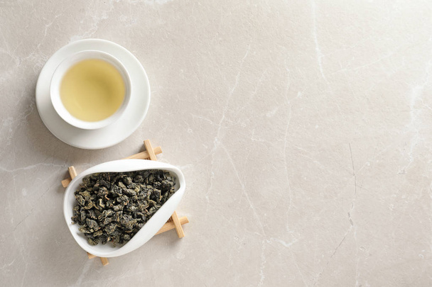 Cup Tie Guan Yin oolong en chahe met thee bladeren op tafel, bovenaanzicht. Ruimte voor tekst - Foto, afbeelding