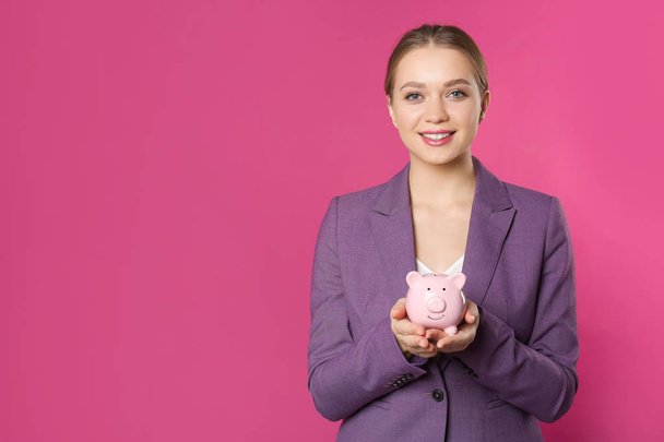 Happy businesswoman with piggy bank and space for text on color background. Money saving - Photo, image