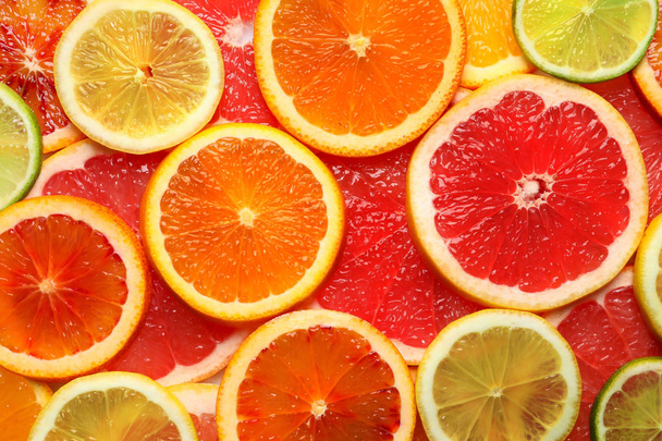 Slices of fresh citrus fruits as background, top view - Фото, изображение