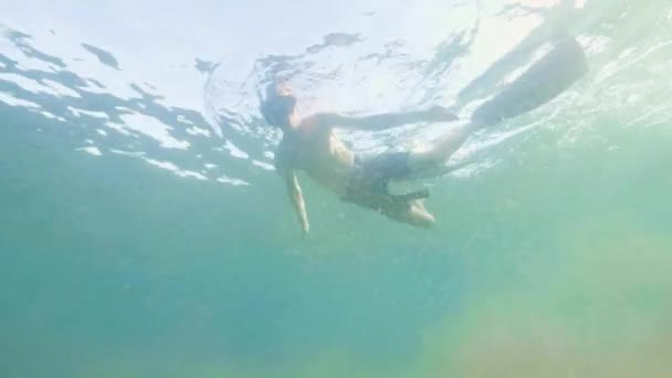 Young man swimming in snorkel mask and tube and shooting selfie video. Portrait man snorkeling in mask and snorkel under transparent sea water. - Footage, Video