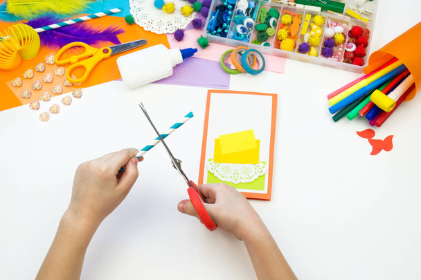 Child makes a postcard with a picture of a cake. Kid paperwork. - 写真・画像