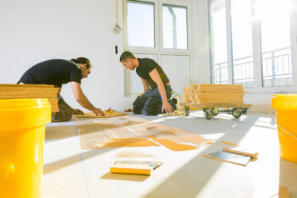 家庭改善中にオーク寄木細工の床を設置するプロの男性労働者   - 写真・画像