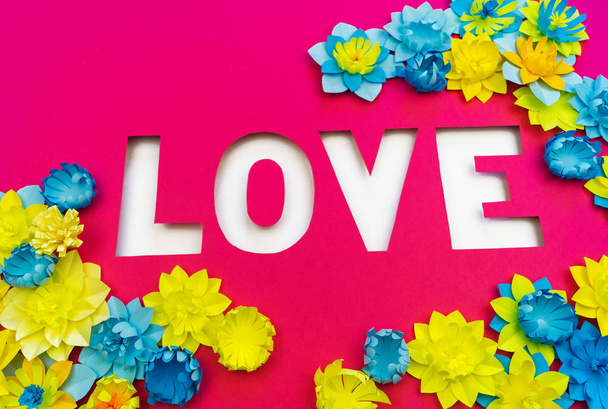 Inscription Love cut out of paper. Pink background. Flower made of paper. - Photo, Image