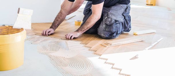 male worker varnishing oak parquet floor during home improvement - Φωτογραφία, εικόνα