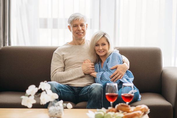 Cena romantica di coppia d'amore adulta a casa. Maturo marito e moglie seduti sul divano e embrancing, famiglia felice
 - Foto, immagini