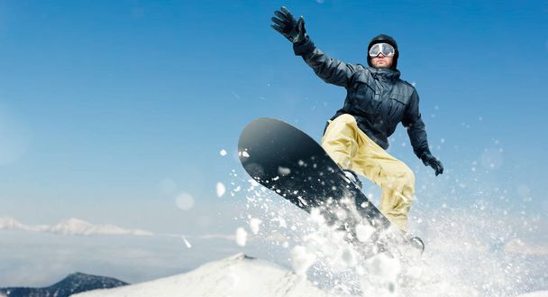 Snowboarder męski, niebezpieczny zjazd w akcji, widok z przodu. Snowboarding jest sportem ekstremalne zima. Człowiek na snowboardzie w skoku - Zdjęcie, obraz