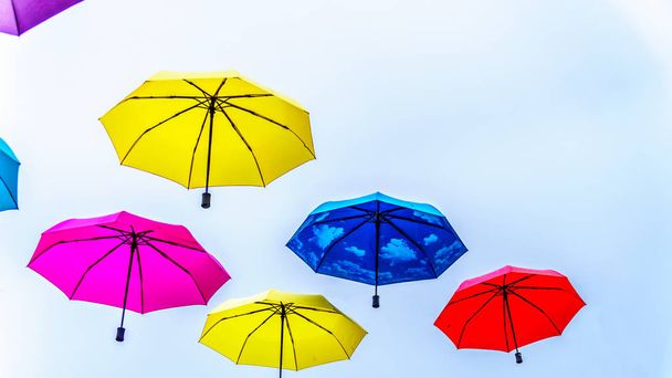 Πολύχρωμες ομπρέλες επιπλέουν στον αέρα κάτω από συννεφιασμένο ουρανό - Φωτογραφία, εικόνα