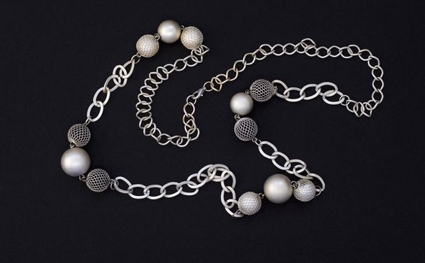 collar moderno para mujer en forma de cadena y bolas sobre fondo negro
 - Foto, imagen