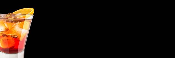 Delicioso coquetel forte na moda alcoólico com a decoração de cor-de-laranja em um fundo preto. Banner de formato amplo
. - Foto, Imagem