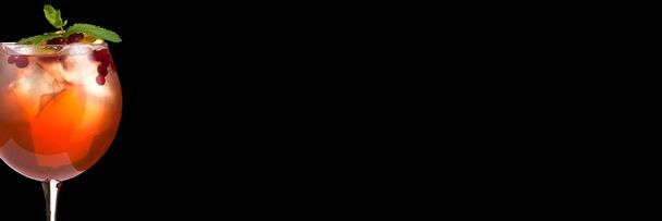 Вкусный алкогольный модный коктейль с декорированием ягод и свежей мяты на черном фоне. Широкий формат
. - Фото, изображение