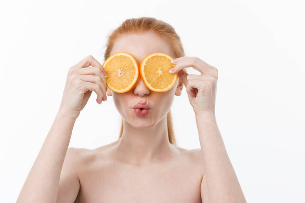 Чудова їжа для здорового способу життя. Красива молода без сорочки жінка тримає шматок апельсина, що стоїть на білому тлі
. - Фото, зображення