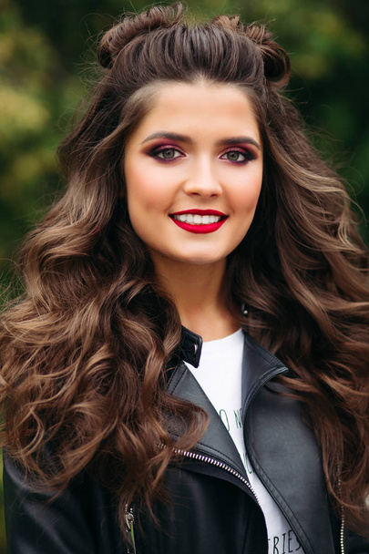 Beautiful woman with long curly hair in leather jacket. - Photo, Image