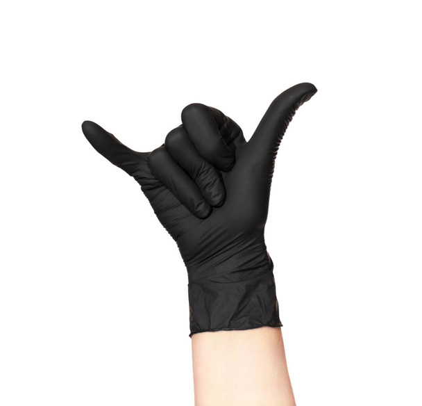 Una mano en un guante negro aislado sobre un fondo blanco muestra un gesto de Shaka: el dedo meñique y el pulgar sobresalen, los otros dedos se presionan
 - Foto, imagen