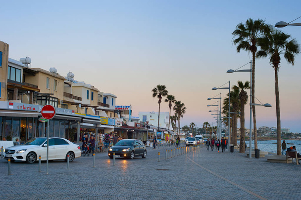 PAPHOS, CYRPUS - FEBRUARY 13, 2019: People walking by Cyprus promenade at twilight. Paphos - famous tourist destination in Cyprus - Foto, Imagen