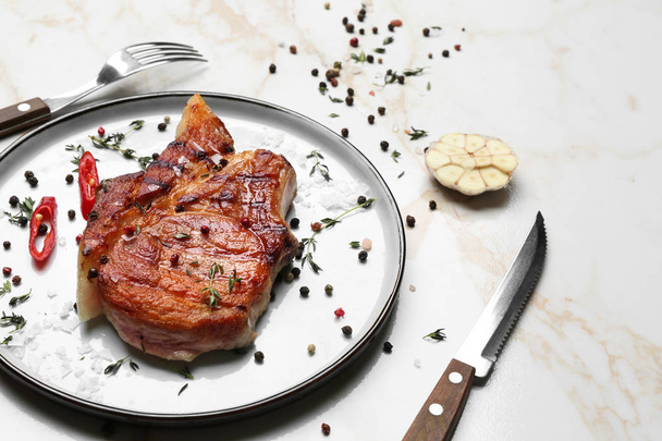 Teller mit schmackhaftem gekochtem Fleisch und Gewürzen auf hellem Hintergrund - Foto, Bild