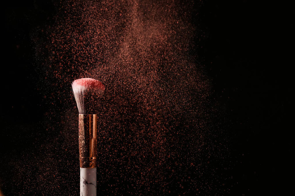 Makeup brush and burst of eyeshadows on dark background - Фото, зображення