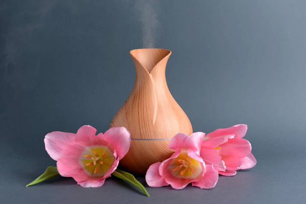 Aroma oil diffuser and flowers on grey background - Photo, Image