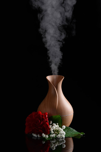Aroma olie diffusor en bloemen op een donkere achtergrond - Foto, afbeelding