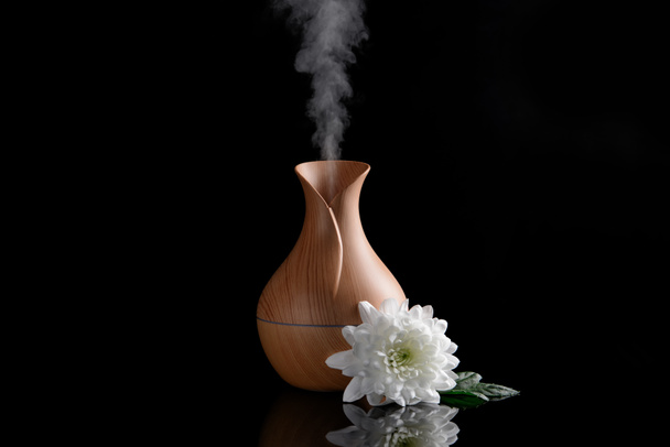 Diffusore di olio aromatico e fiore su sfondo scuro
 - Foto, immagini