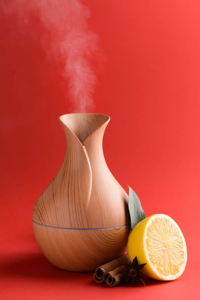Aroma oil diffuser, lemon and cinnamon on color background - Photo, Image
