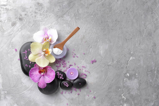 Piedras de spa, flores de orquídea y sal marina sobre fondo gris
 - Foto, Imagen