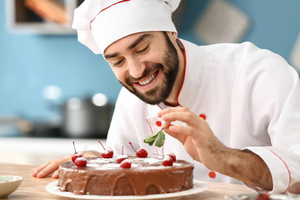 キッチンでおいしいチョコレート ケーキを飾る男性菓子 - 写真・画像