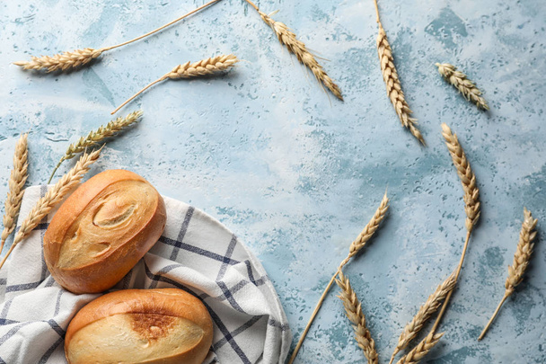 Fresh buns with wheat ears on color background - Photo, Image