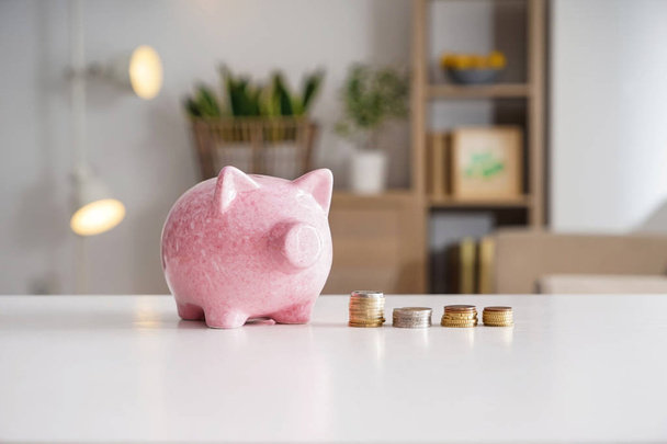 Piggy bank and coins on table. Concept of savings - Fotoğraf, Görsel