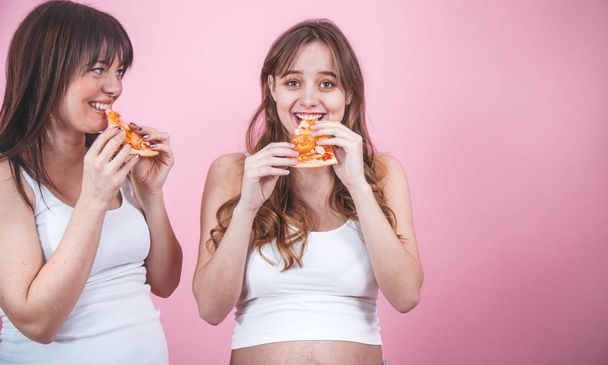 nutrition concept, pregnant women eating pizza on a pink background - Foto, Imagem