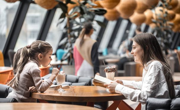 glückliche junge Mütter mit Kindern sitzen am Esstisch und unterhalten sich im Restaurant - Foto, Bild