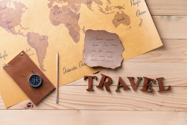 Notebook, old paper sheet, compass and world map on wooden background. Travel concept - Foto, afbeelding