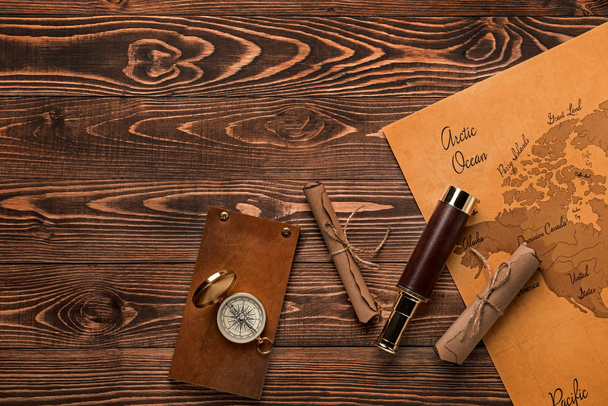 Spyglass, rouleaux, boussole, carnet et carte du monde sur fond en bois. Concept de voyage
 - Photo, image