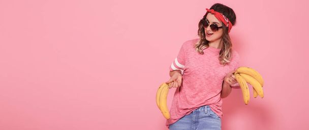 Szép, fiatal lány, rózsaszín póló és vicces banán gazdaság szemüveg - Fotó, kép