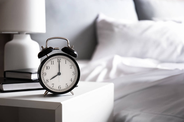 Alarm clock on table in bedroom - Foto, imagen
