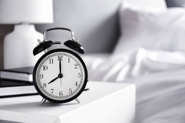 Alarm clock on table in bedroom - Φωτογραφία, εικόνα