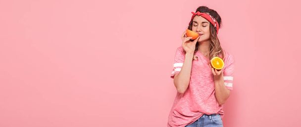 Gyönyörű fiatal lány rózsaszín póló, tartja vicces szexi narancssárga, rózsaszín háttér. Nyár és pihenés - Fotó, kép