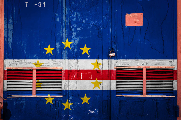 Nahaufnahme eines alten Lagertores mit der Nationalflagge von Kap Verde. Konzept des kapverdischen Export-Imports, der Lagerung von Waren und der nationalen Lieferung von Waren. Flagge im Grunge-Stil - Foto, Bild