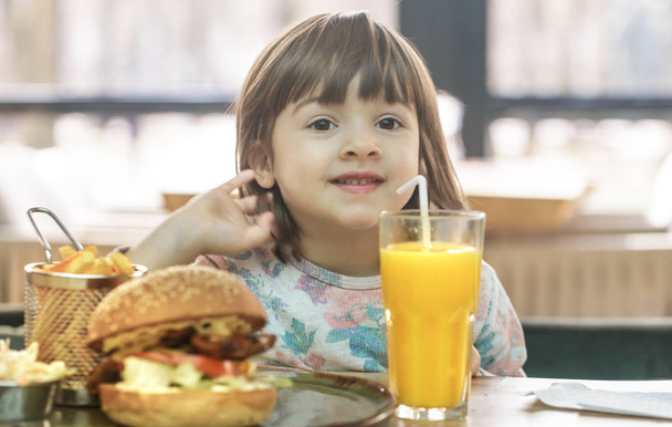 Little girl eats in a fast food cafe - Foto, immagini