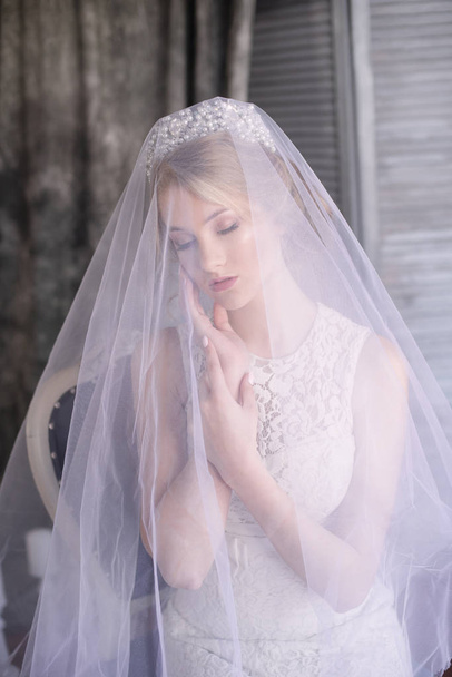 Young beautiful bride with blond hair in a diadem and white veil and white dress - Foto, Imagem