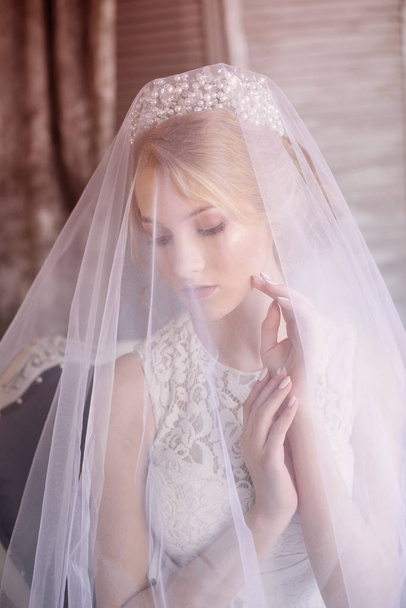 Young beautiful bride with blond hair in a diadem and white veil and white dress - Φωτογραφία, εικόνα