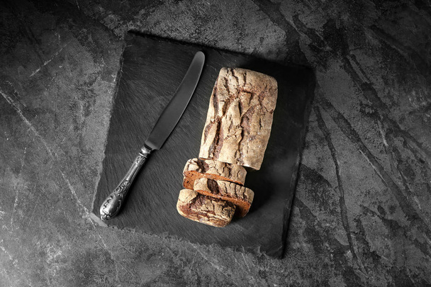 Slate plate with tasty fresh bread on grey table - Фото, изображение