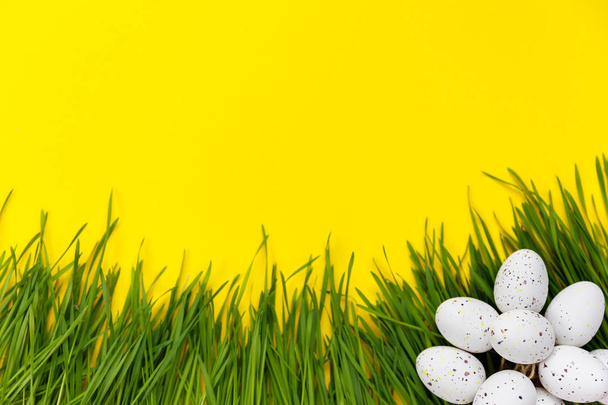 Easter decor. Decorative eggs and green grass are laid out on a yellow background - Foto, Imagem