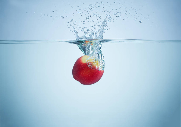 apple falls into the water scattering a lot of splashes and drop - Foto, immagini